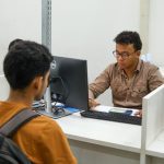 Funcionários do Sine Amazonas atendendo clientes em balcão de atendimento.