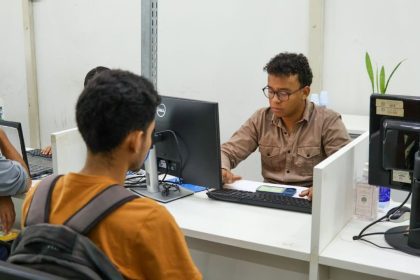 Funcionários do Sine Amazonas atendendo clientes em balcão de atendimento.