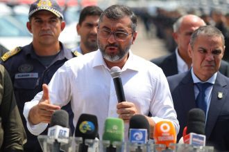 Governador discursa em entrega de viaturas, com oficiais e jornalistas presentes.