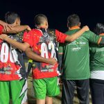 Grupo de pessoas com camisas de times de futebol abraçados, mostrando apoio e união. Taça das Favelas