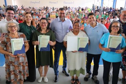 Wilson Lima e Grupo de pessoas posando para foto segurando documentos, com um grande público ao fundo.