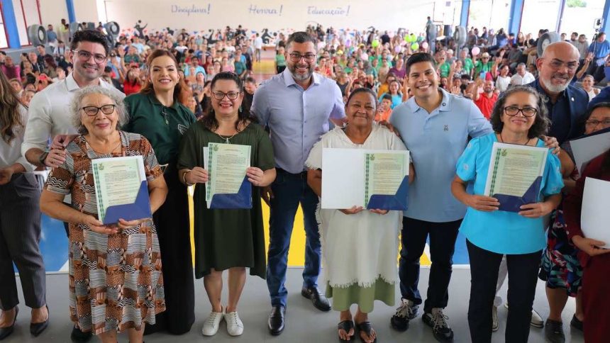 Wilson Lima e Grupo de pessoas posando para foto segurando documentos, com um grande público ao fundo.