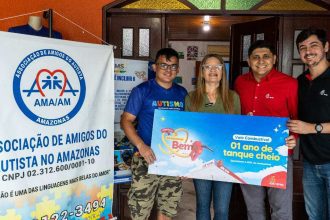 Grupo de pessoas segura vale combustÃvel '01 ano de tanque cheio' da Atem, em apoio à Associação de Amigos do Autista.