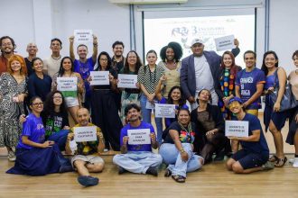 Grupo de pessoas segurando cartazes em evento sobre dança em Manaus.
