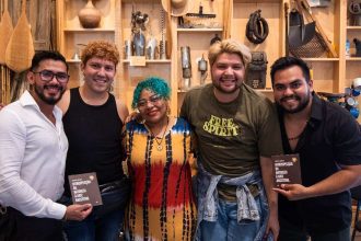 Grupo de pessoas sorrindo com livros, em evento de oficinas gratuitas 'Aglomeração Literária' no Amazonas.