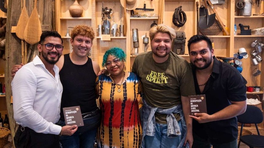 Grupo de pessoas sorrindo com livros, em evento de oficinas gratuitas 'Aglomeração Literária' no Amazonas.