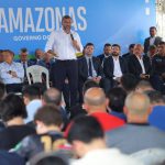 Wilson Lima fala ao microfone em evento do governo do Amazonas, com público e autoridades presentes.