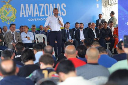 Wilson Lima fala ao microfone em evento do governo do Amazonas, com público e autoridades presentes.