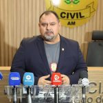 Homem fala em coletiva de imprensa sobre Operação Shamar com microfones à frente.