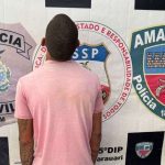 Homem preso em frente a distintivos da polícia.