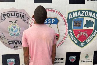 Homem preso em frente a distintivos da polícia.