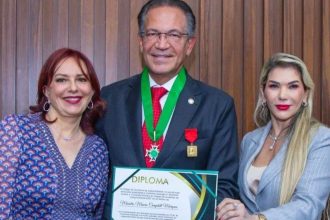 Homem recebe diploma ladeado por duas mulheres, celebrando sua dedicação à Justiça.