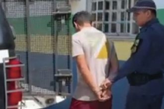 Homem sendo preso por policial, suspeito de homicídio no Amazonas
