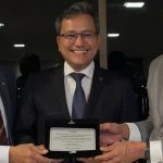 Homenagem a Dr. Edmison Jukiyama Barroso pela Receita Federal, com três homens sorrindo e segurando uma placa.