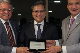 Homenagem a Dr. Edmison Jukiyama Barroso pela Receita Federal, com três homens sorrindo e segurando uma placa.