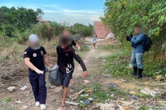 Homens carregam corpo em construção abandonada, em notícia sobre achado.