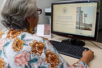 Idosa consultando cartilha de proteção contra fraudes financeiras para idosos em computador.