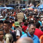 Imagem de multidão em rua comercial, possivelmente em Manaus.