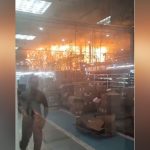 Incêndio em fábrica: funcionários correm em meio às chamas e fumaça.