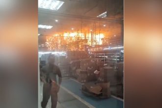 Incêndio em fábrica: funcionários correm em meio às chamas e fumaça.
