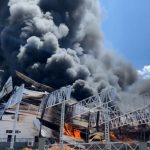 Incêndio em fábrica no Distrito Industrial II, com densa fumaça preta e fogo.