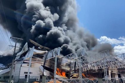 Incêndio em fábrica no Distrito Industrial II, com densa fumaça preta e fogo.