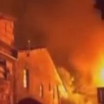 Incêndio em residência com chamas alaranjadas e fumaça densa.