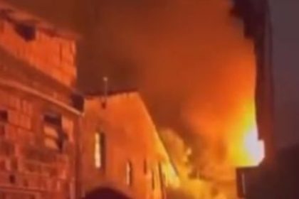 Incêndio em residência com chamas alaranjadas e fumaça densa.