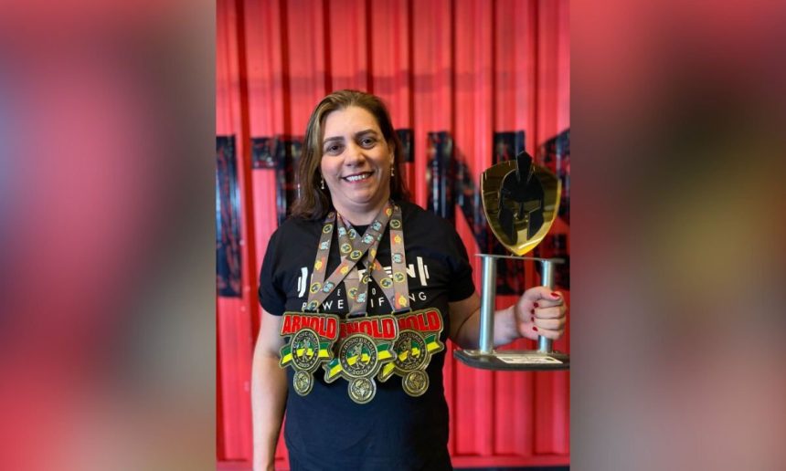 Karen Peixoto com medalhas e troféu, celebrando recorde brasileiro no Power Bíceps Strict Curl.