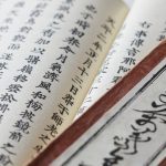 Livro antigo com caracteres japoneses em foco, detalhes da escrita e da capa.