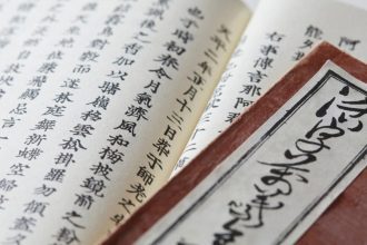 Livro antigo com caracteres japoneses em foco, detalhes da escrita e da capa.