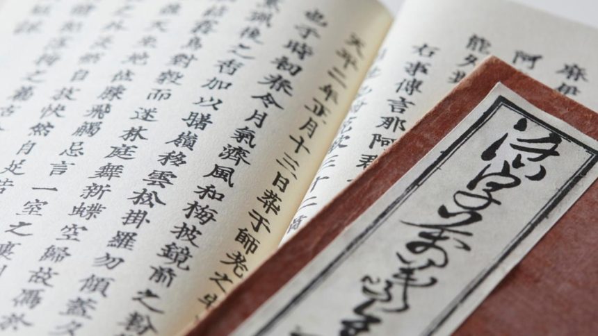 Livro antigo com caracteres japoneses em foco, detalhes da escrita e da capa.
