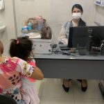 Mãe e criança em consulta médica, com profissional usando máscara.