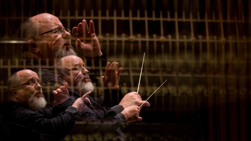Maestro conduzindo orquestra, com efeito de múltiplas exposições, usando uma batuta e vestindo roupa preta.