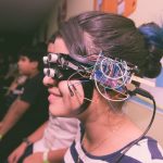 Menina usando óculos de realidade virtual caseiro com fios e componentes eletrônicos.
