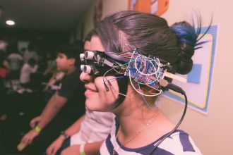 Menina usando óculos de realidade virtual caseiro com fios e componentes eletrônicos.