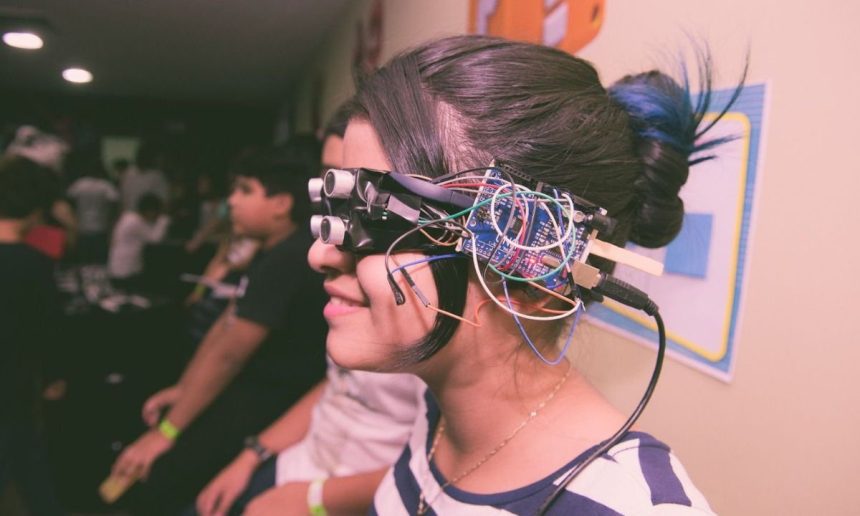 Menina usando óculos de realidade virtual caseiro com fios e componentes eletrônicos.