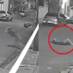 Mulher caída no chão após agressão. Cena de câmera de segurança mostra vítima após ataque com capacete.