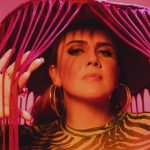 Mulher com chapéu de franjas em cenário rosa