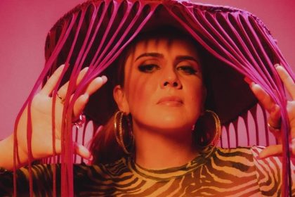 Mulher com chapéu de franjas em cenário rosa