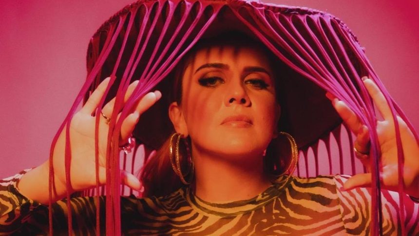 Mulher com chapéu de franjas em cenário rosa