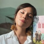Mulher com livro 'Territórios de Mim' de Rakel Caminha