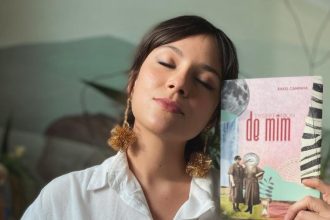 Mulher com livro 'Territórios de Mim' de Rakel Caminha