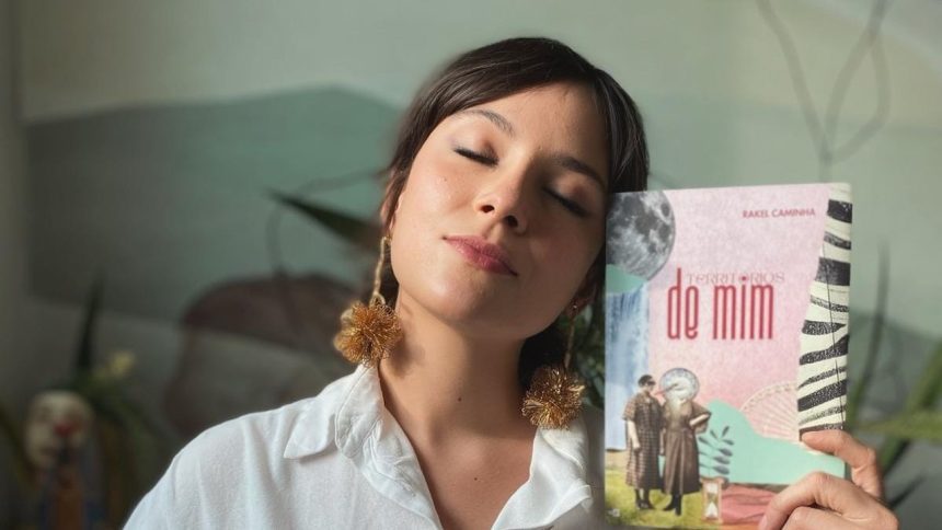 Mulher com livro 'Territórios de Mim' de Rakel Caminha