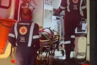 Mulher em maca sendo socorrida por equipe do SAMU dentro de ambulância.