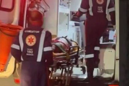 Mulher em maca sendo socorrida por equipe do SAMU dentro de ambulância.