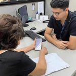 Mulher idosa mostra smartphone para funcionário em escritório da Amazonprev