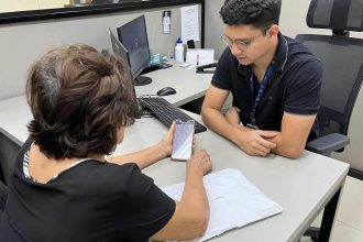 Mulher idosa mostra smartphone para funcionário em escritório da Amazonprev