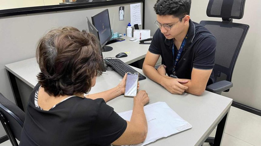 Mulher idosa mostra smartphone para funcionário em escritório da Amazonprev