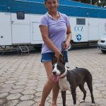 Mulher sorrindo com cachorro em frente a trailer CCZ, o Castramóvel da Prefeitura de Manaus